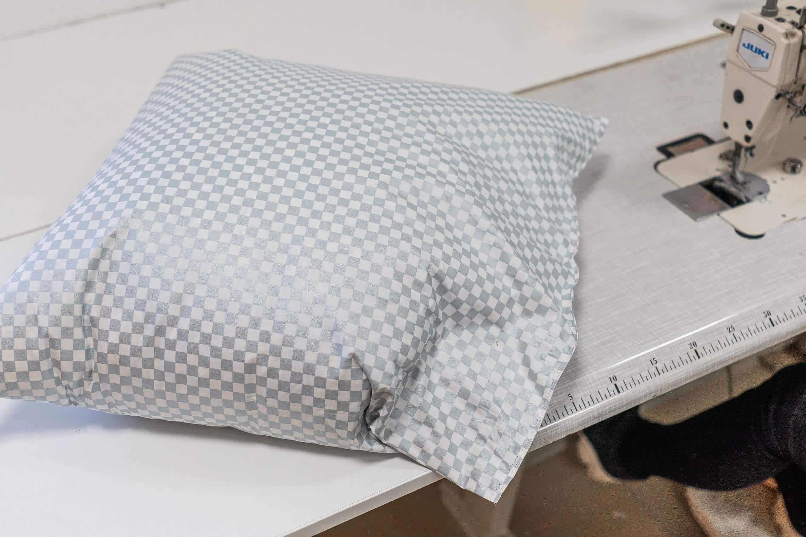 Pernă din pene cu dos nou, lângă mașina de cusut din atelierul Sanitar